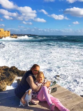 Mamma som kramar sin dotter vid havet