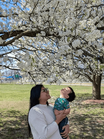 Mamma som håller sin son under ett blommande träd