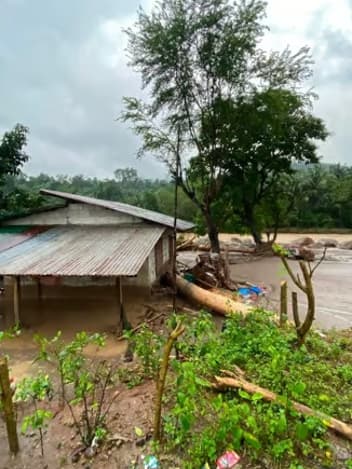 Flood-damaged house beside a swollen river