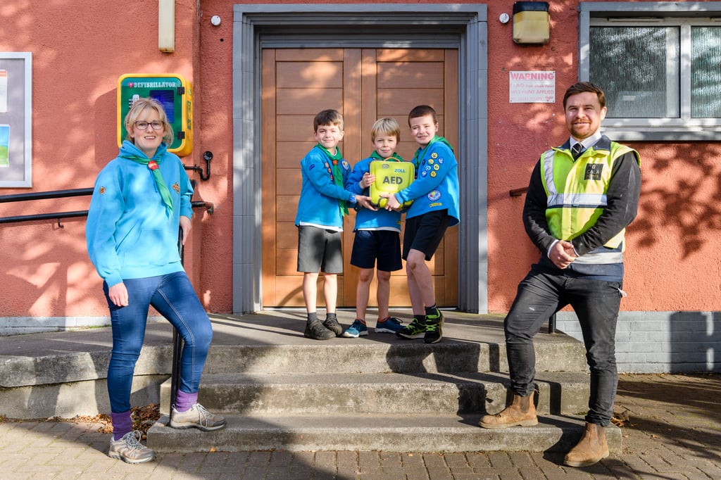 property PR photography, The Gullane Beavers have raised money for defibrillators in Gullane with the help of a £1k donation from CALA Homes (East).Jude Leslie and Kids from the Beavers group with Site Manager Danny Owenson at Gullane Village Hall – where one of the defibs will be based.