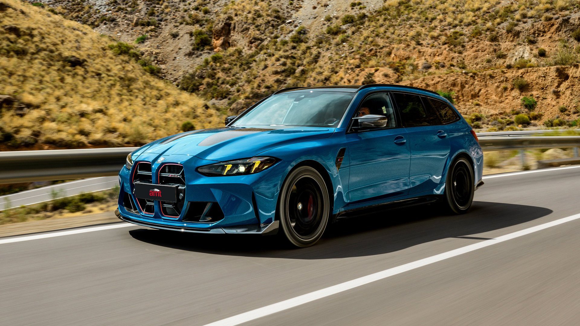 The BMW M3 CS Touring driving on an open road, highlighting its bold aerodynamic features, carbon-fibre elements, and distinctive, red-accented kidney grilles.