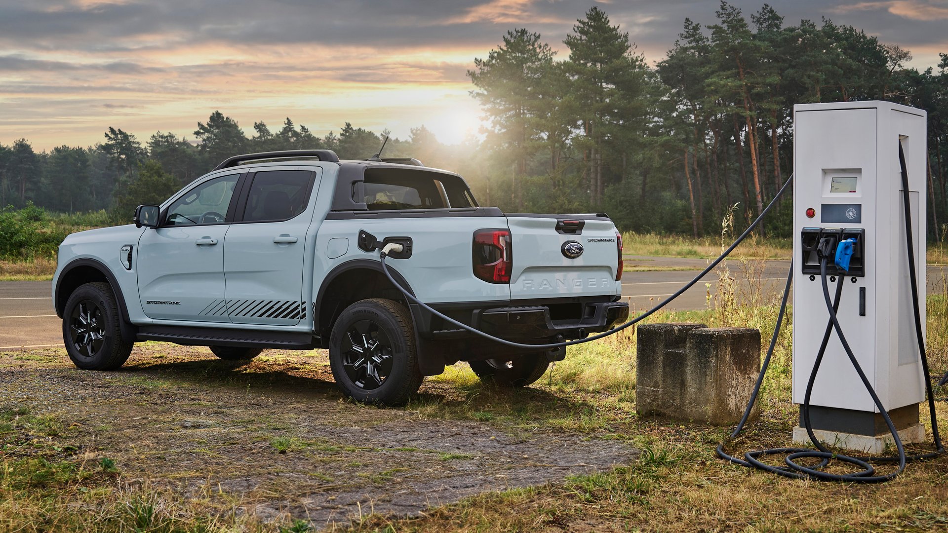 The Ford Ranger PHEV charging at a public station during sunset, emphasising its plug-in hybrid technology