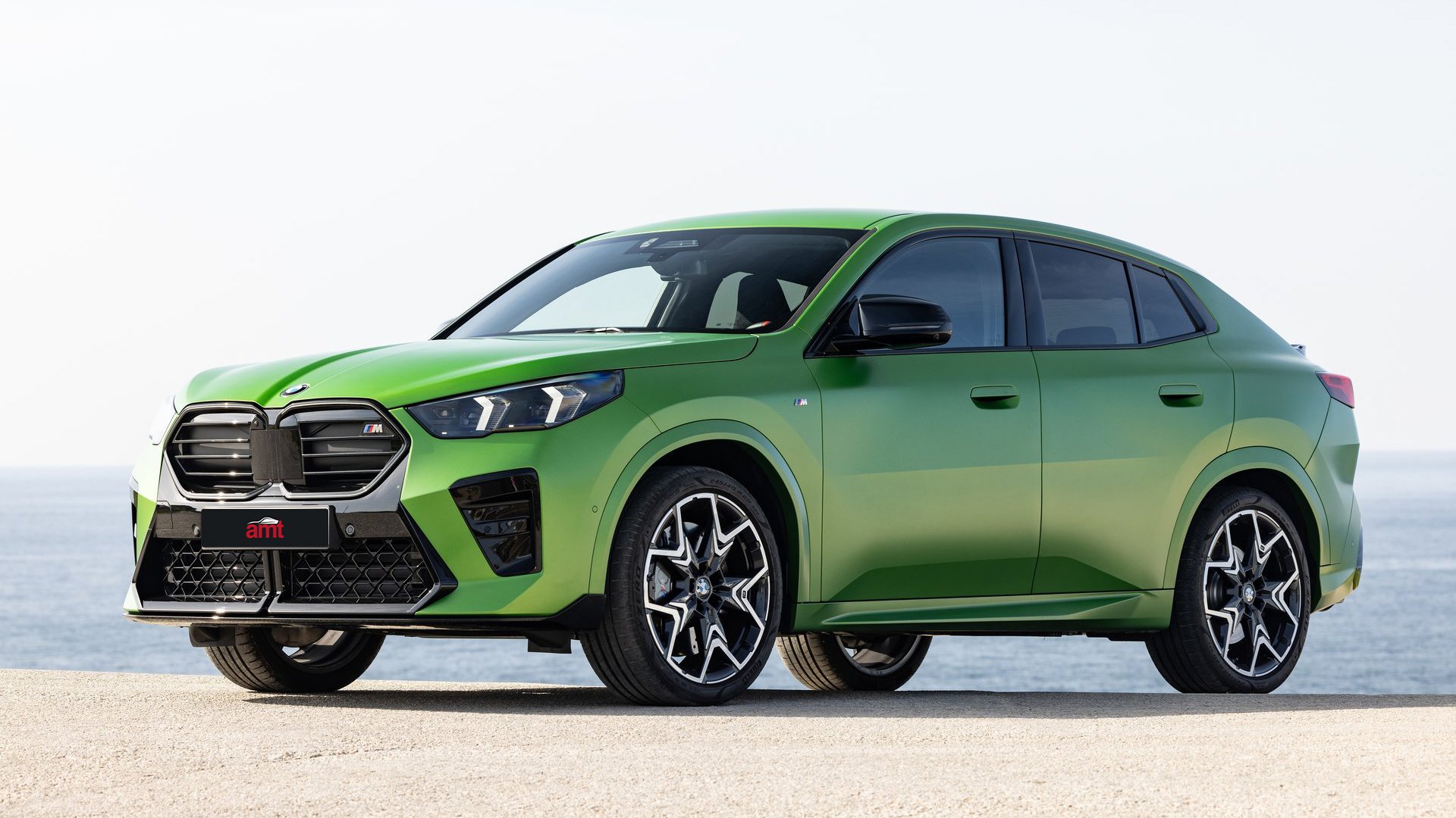 A bold green BMW X2 M, positioned with a coastal horizon in the background, combining athleticism and innovation for 2025.