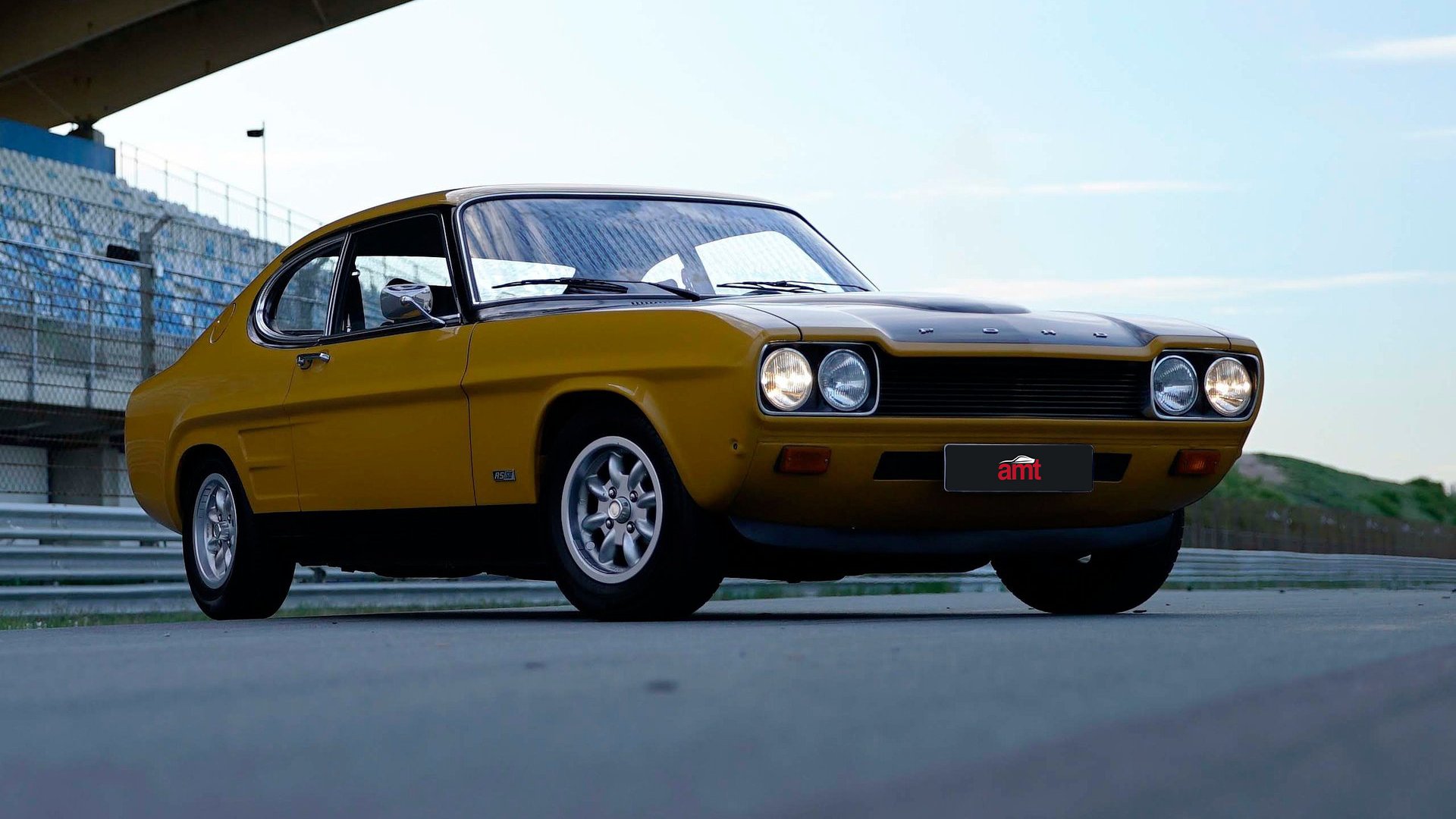 A vintage Ford Capri from the 1970s, parked on a racetrack, emphasising its classic styling and heritage appeal with the iconic two-door coupe design.