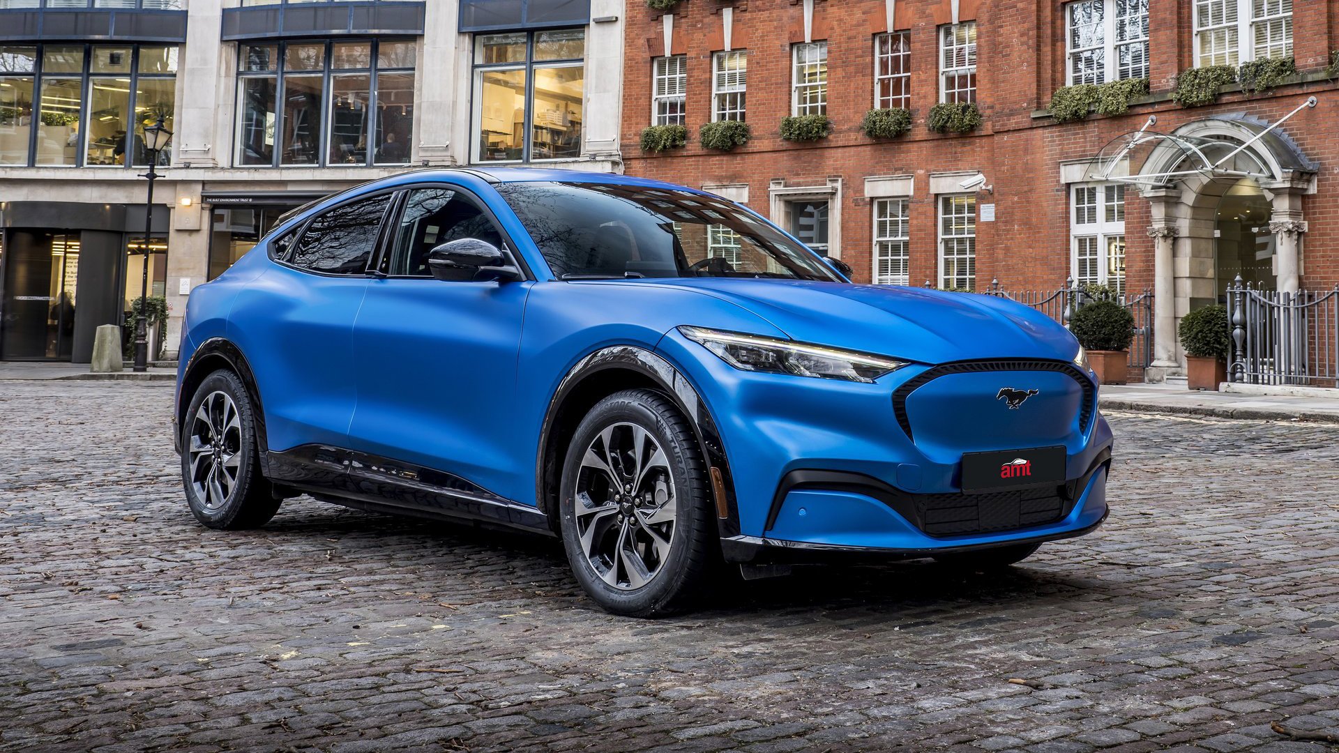 The electric blue Ford Mustang Mach-E, blending iconic design with modern innovation, showcased in a 2025 urban environment.