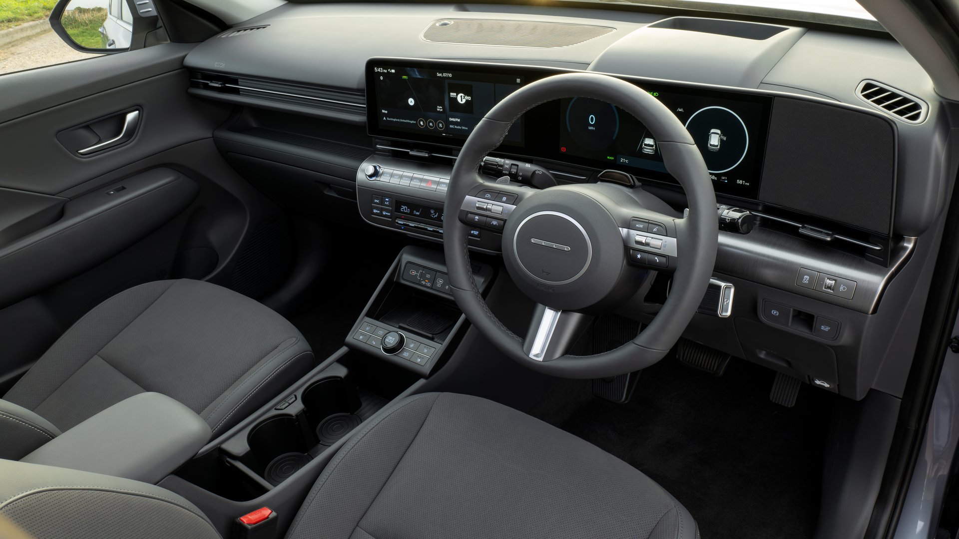 Interior view of the Hyundai Kona Electric, highlighting its smartly designed dashboard with intuitive controls, a fully digital driver display, and a sleek touchscreen interface for a modern driving experience.