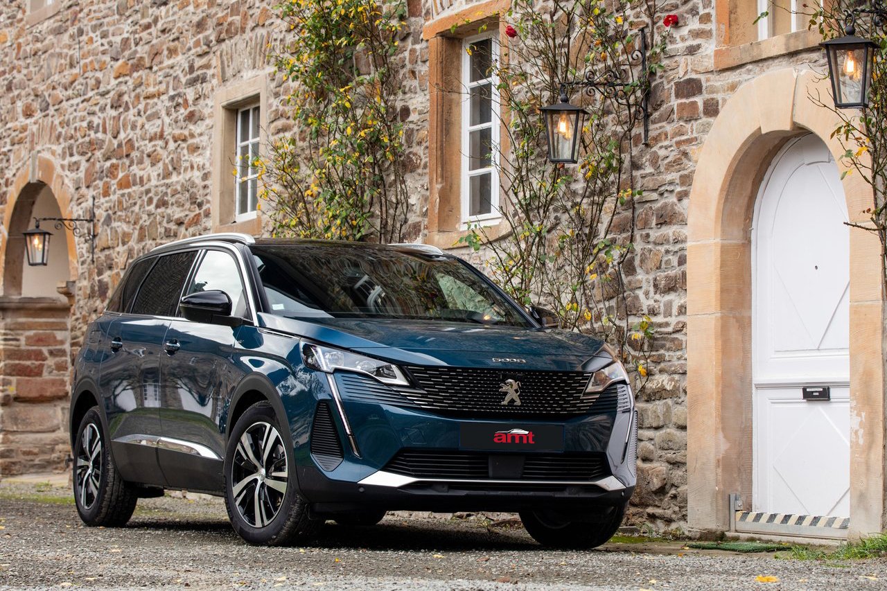 Peugeot 5008 parked beside a rustic stone building, highlighting its elegant design and family-friendly size.