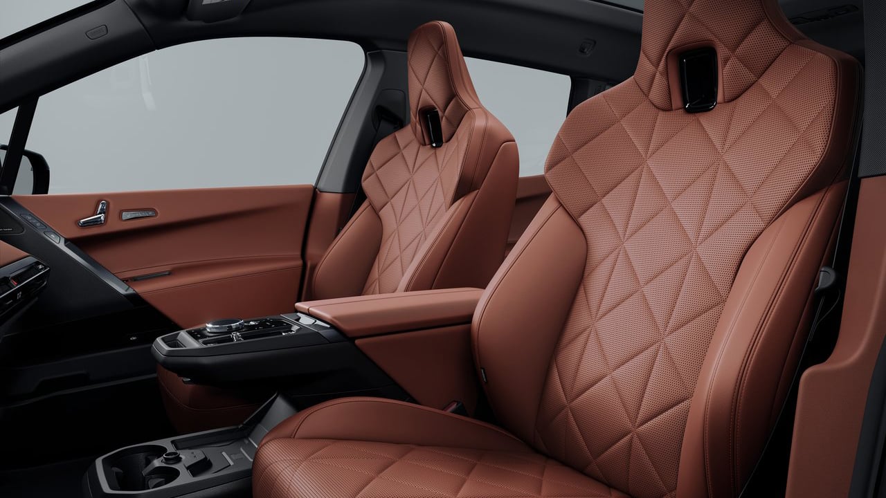 Close-up of the luxurious front seats in the 2025 BMW iX, featuring quilted brown leather upholstery.