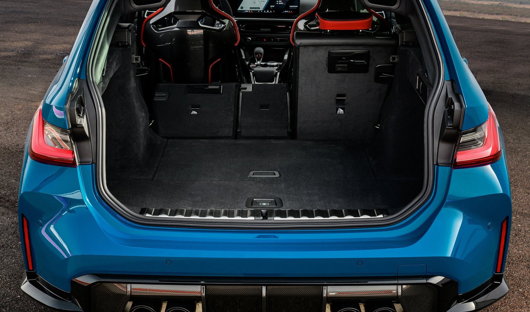 The spacious boot area of the BMW M3 CS Touring, showcasing its blend of practicality and high-performance design with foldable rear seats and carbon fibre trim.