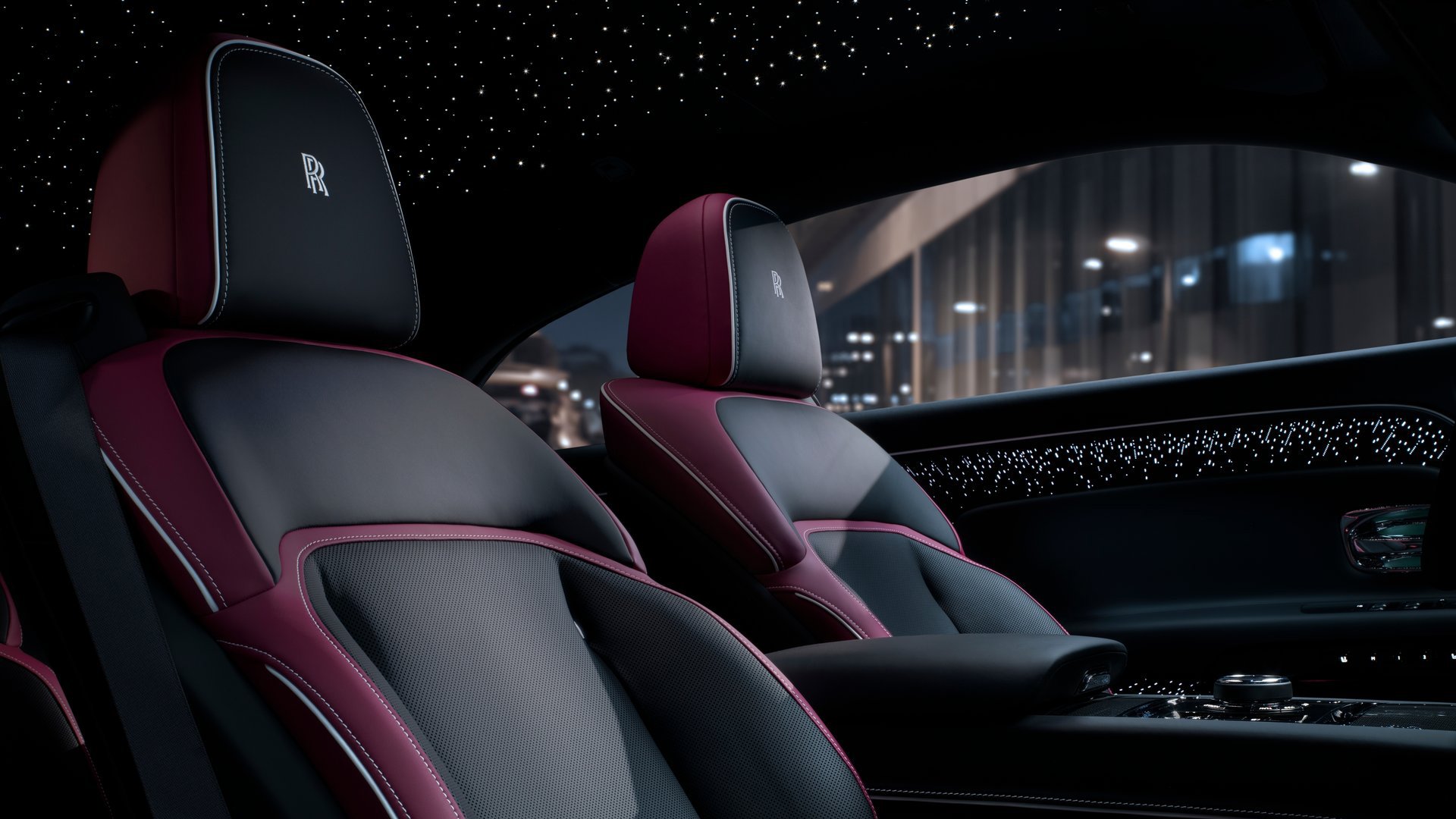 Interior shot of the Rolls-Royce Spectre Black Badge, featuring plush black and burgundy leather seats, ambient starlight ceiling, and high-end bespoke materials.