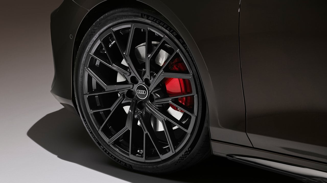 The Audi A6 Avant's black alloy wheels with red brake callipers, emphasizing its sporty performance and precision engineering.