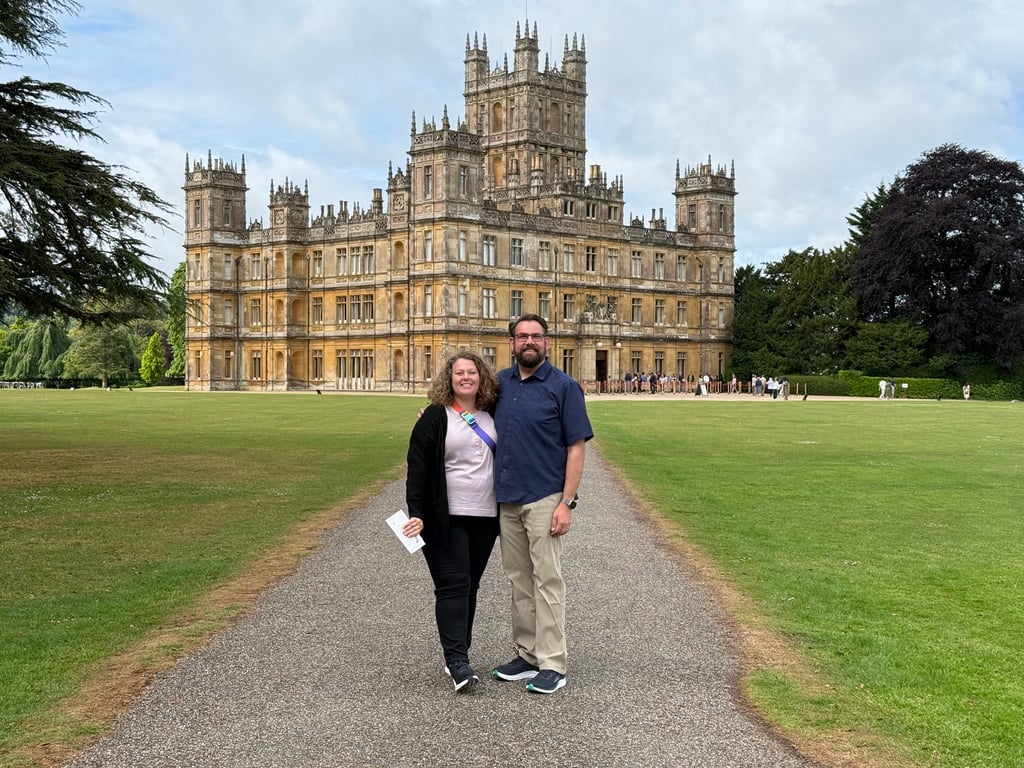 Couple posing on the gravel path leading to the grand facade of Highclere Castle