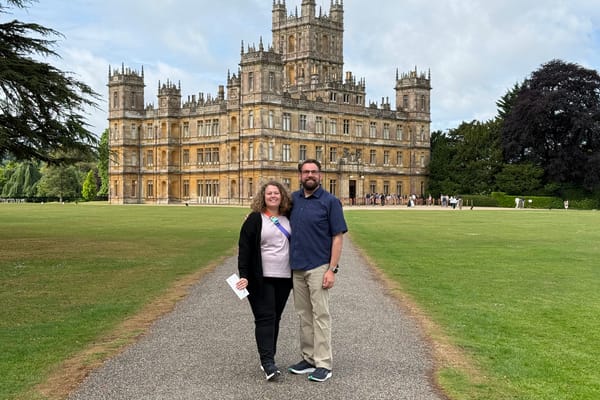 Couple posing on the gravel path leading to the grand facade of Highclere Castle