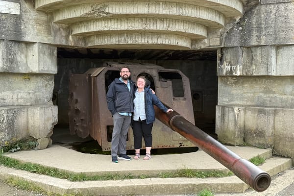 Couple standing in front of a large WWII-era gun emplacement in a concrete bunker