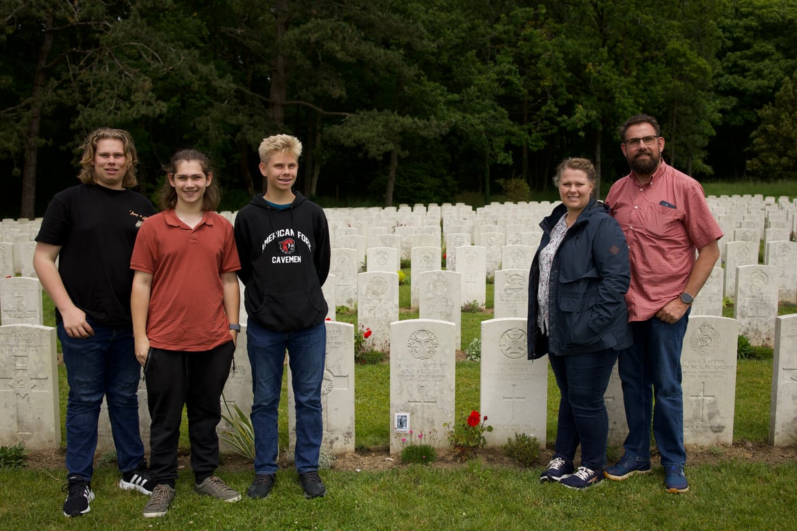 Family of five standing among white headstones at a Commonwealth war cemetery in France