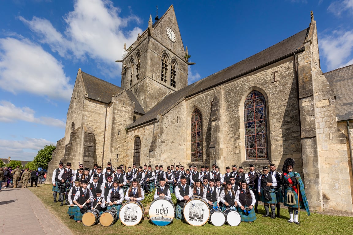 Utah Pipe Band posed in front of the Sainte-Mere-Eglise church in Normandy, France