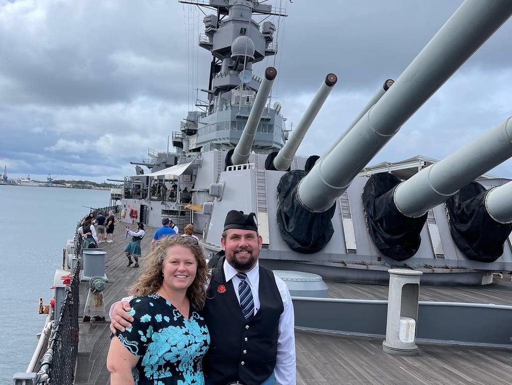 Couple posing on the deck of the USS Missouri with the ship's main gun turrets behind them