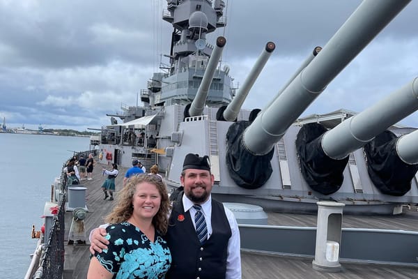 Couple posing on the deck of the USS Missouri with the ship's main gun turrets behind them