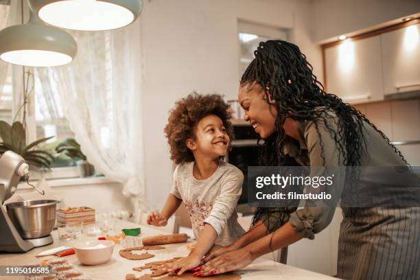 Cute 5 years old girl making cookies for Christmas with her mom.