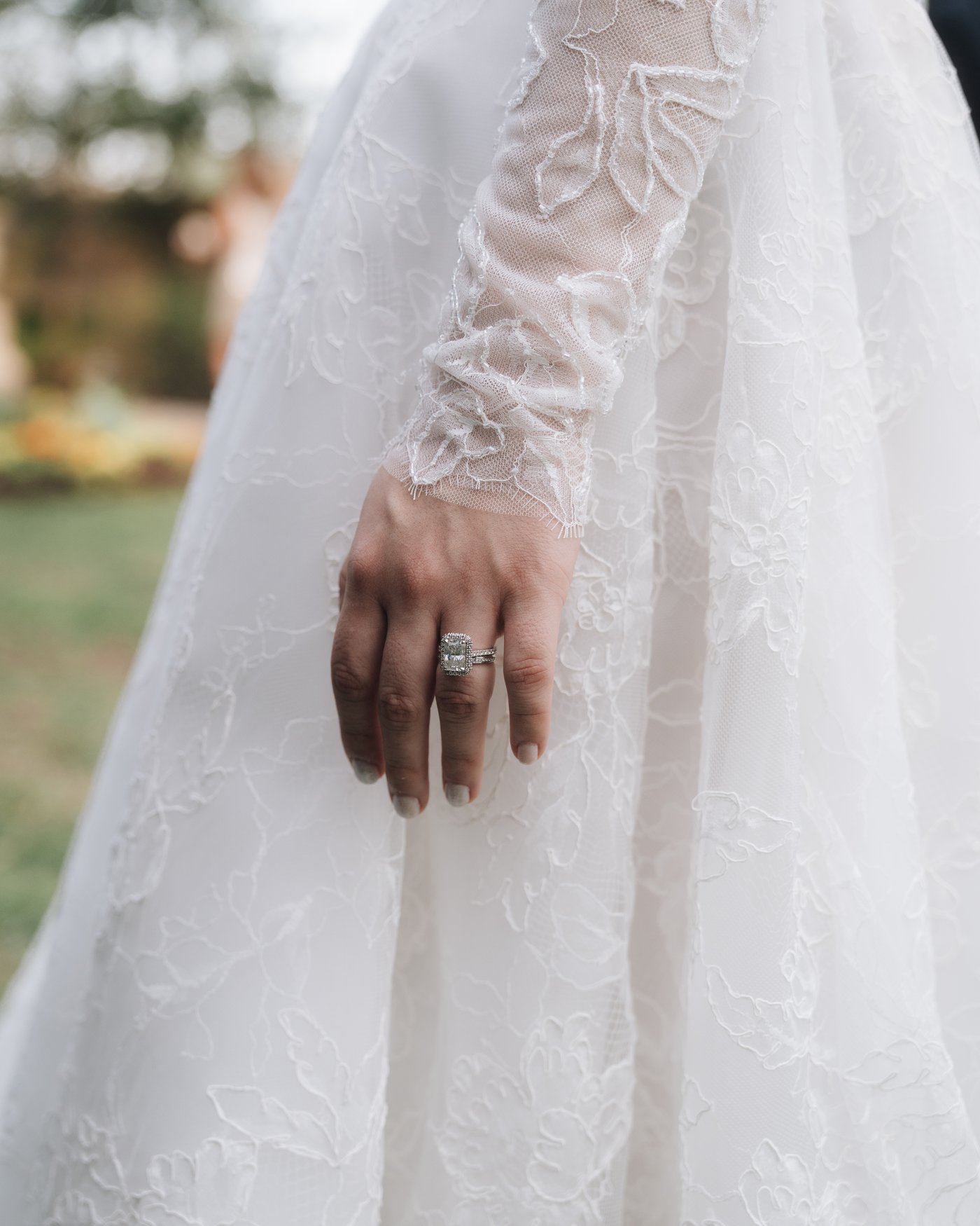Close on the bride's hand and ring against the lace of her gown