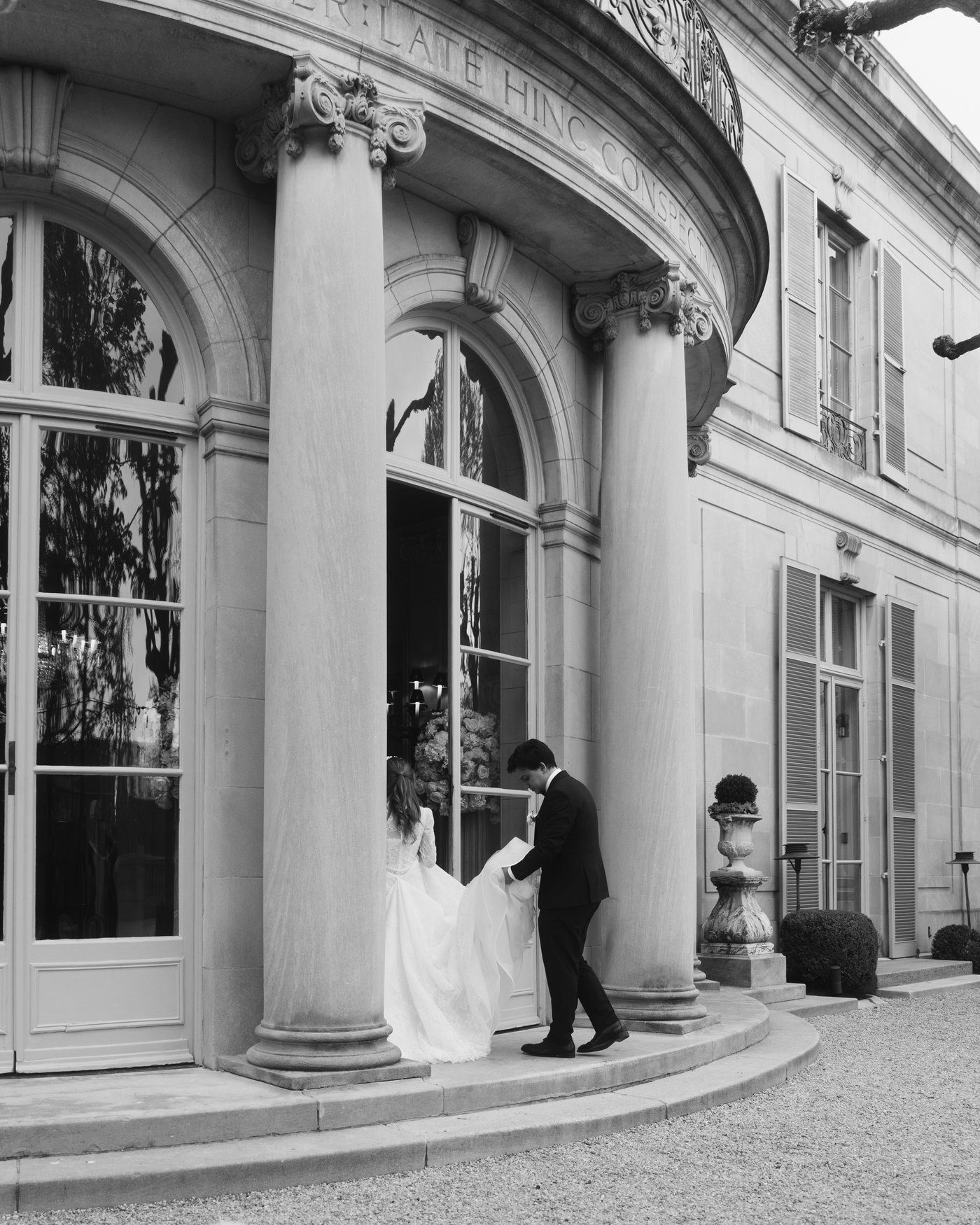 Black and white, the couple on the curved stone steps at the front of the house