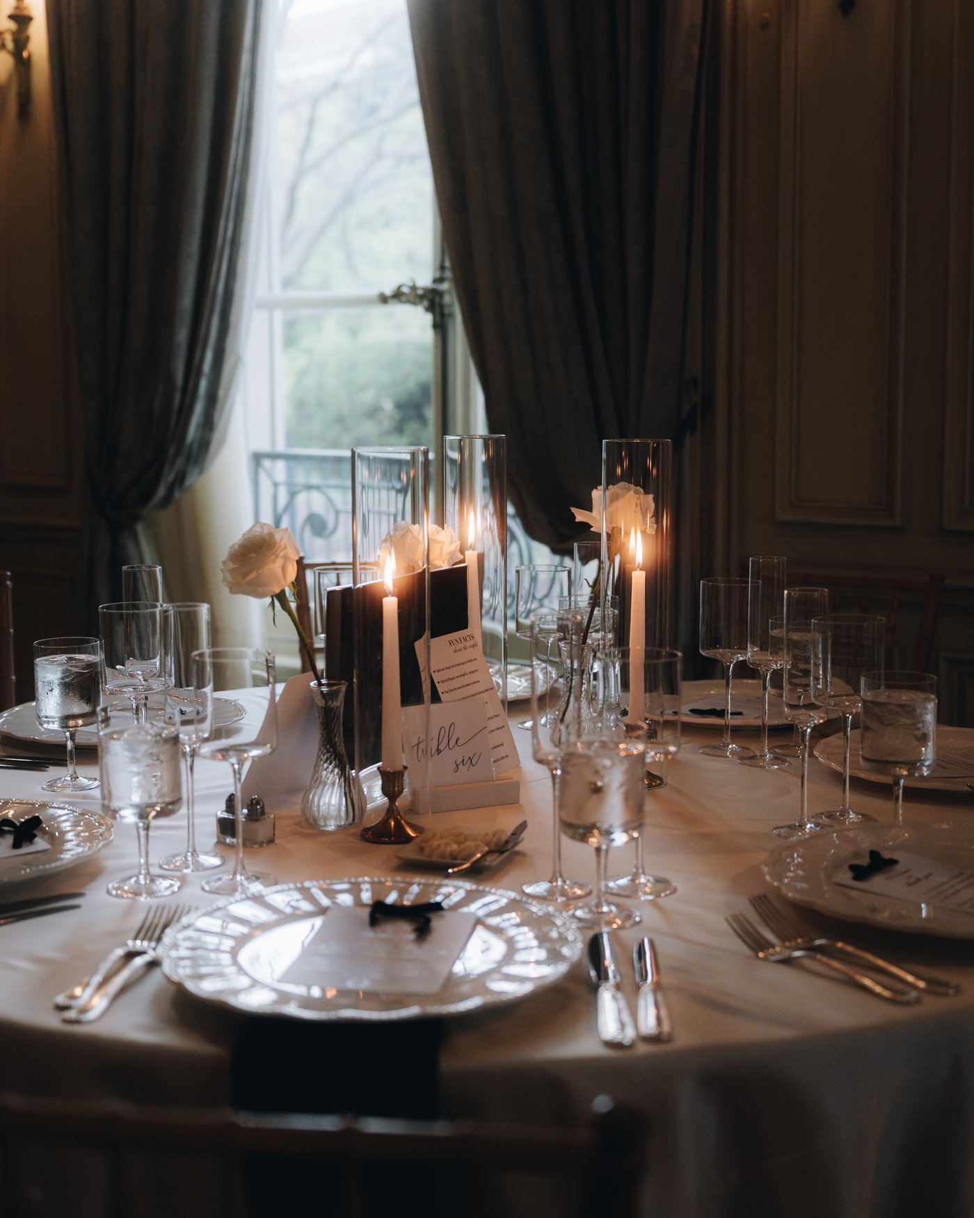 A place setting close up, black tapers and crystal on white linen
