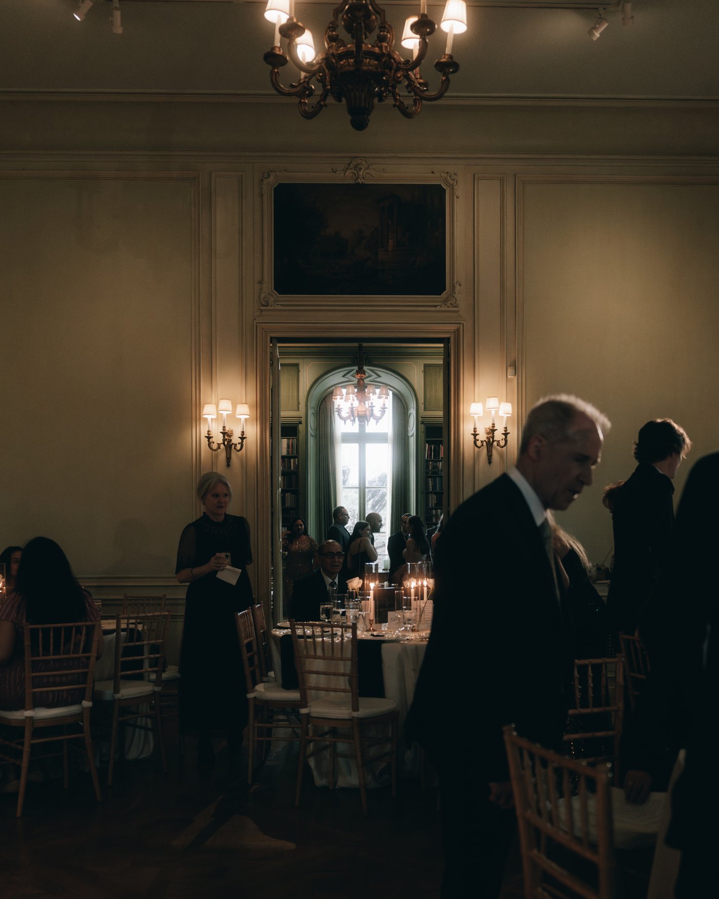 The reception room filling with guests under the chandeliers