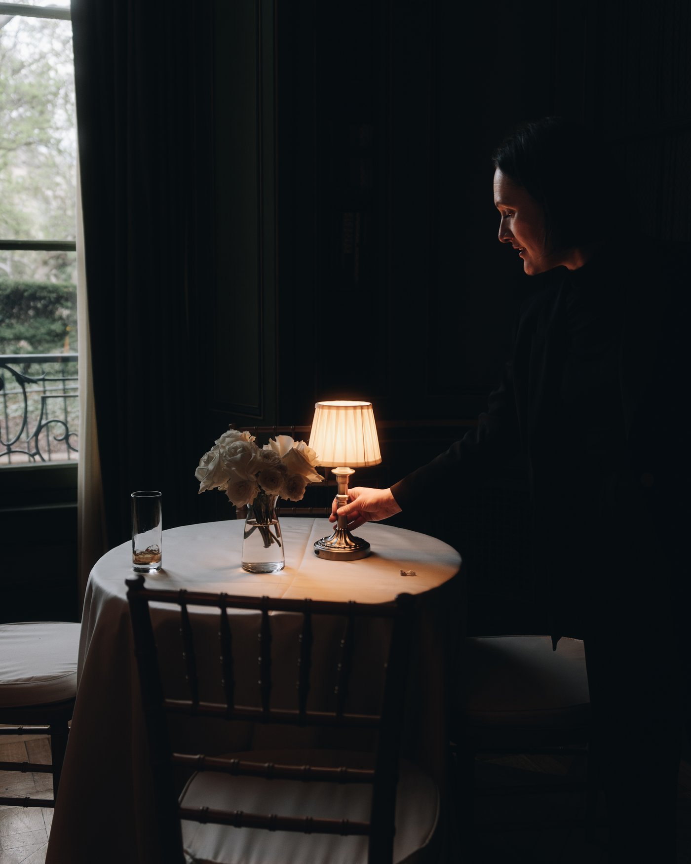 A single lamp and a low arrangement of flowers on a side table