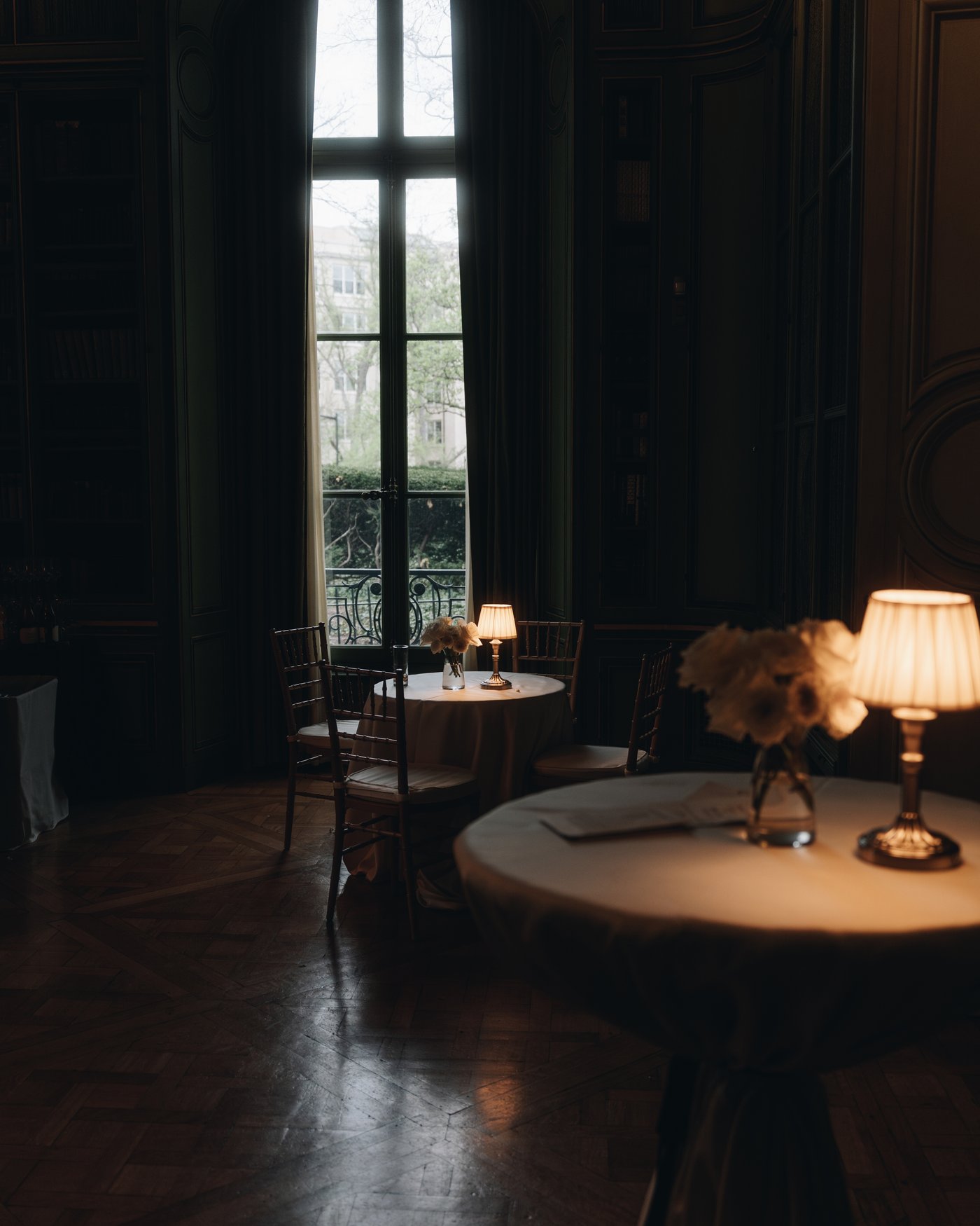 A round table lit by one lamp in a dark panelled room