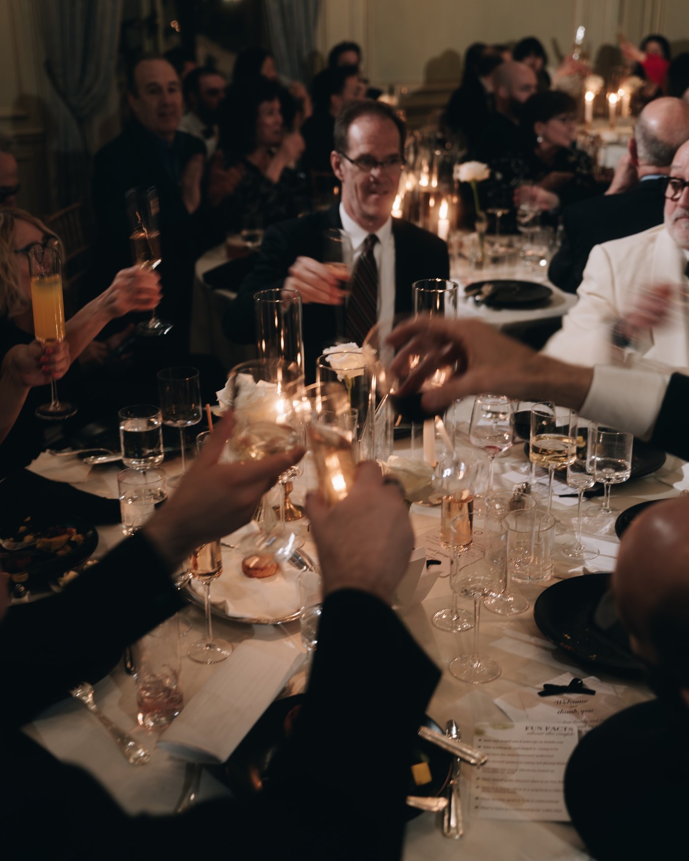 Guests raising their glasses across the candlelit table