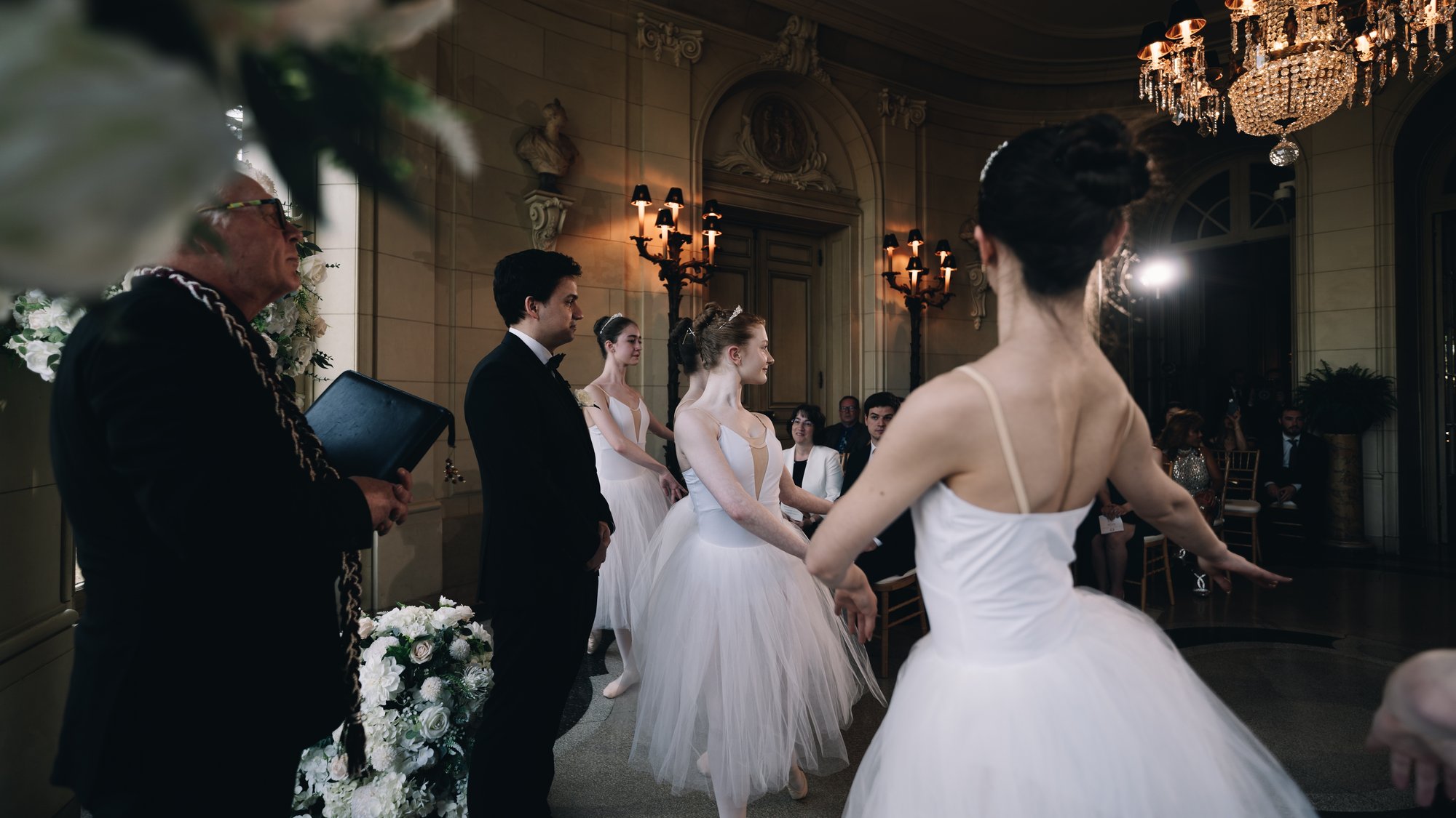 Ballerinas in white performing during the ceremony in front of the seated guests