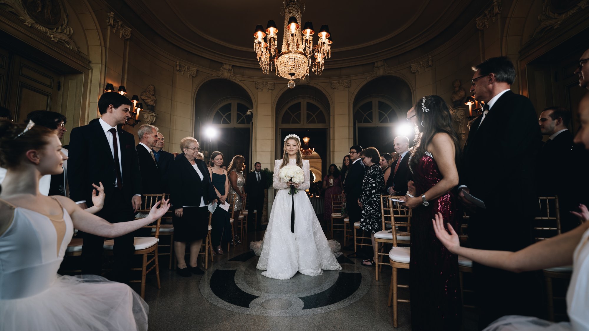 The bride in the middle of the ballroom floor with the guests gathered around