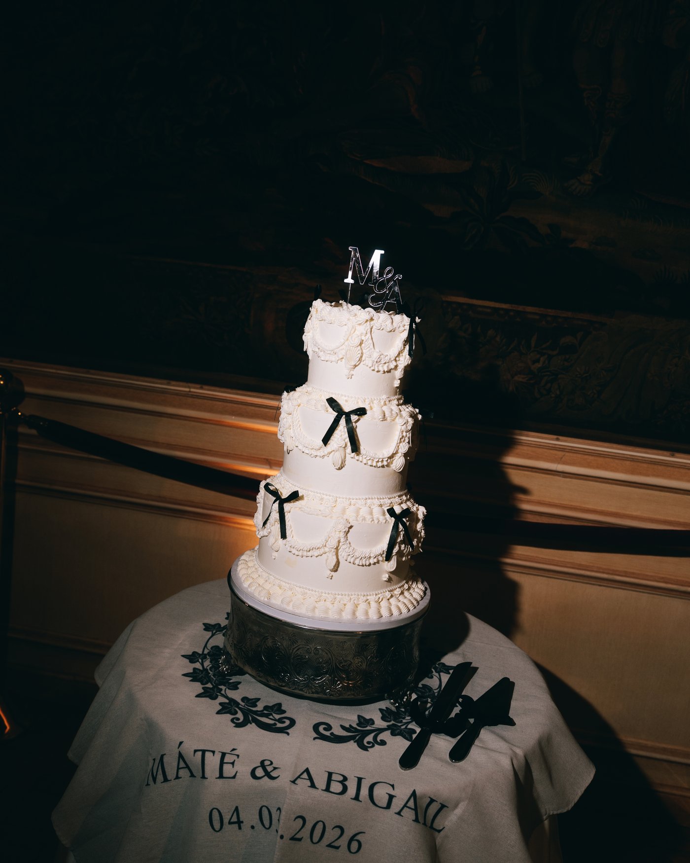 The tiered white cake tied with black bows, both their names and the date painted across the front