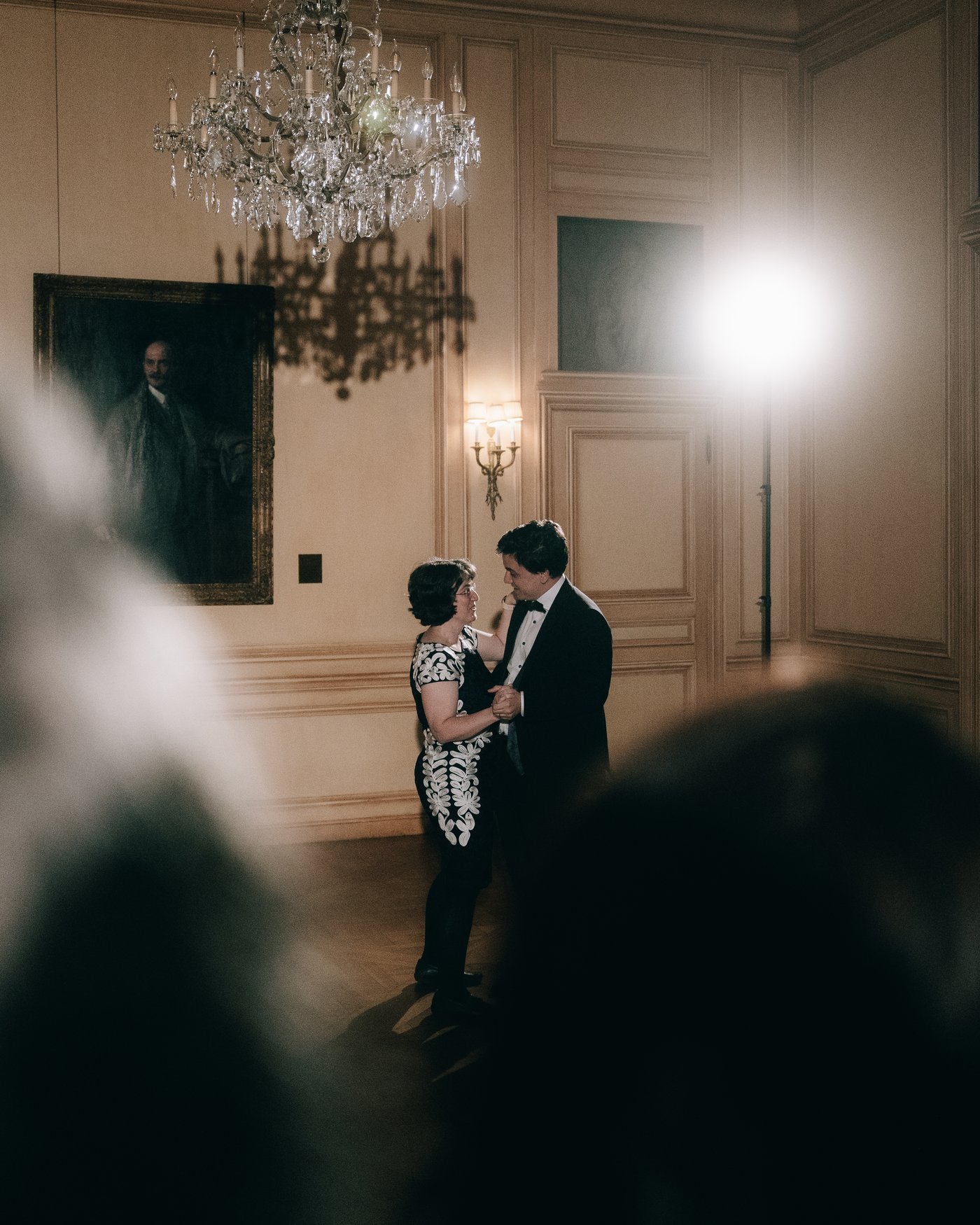 The couple dancing in the dark ballroom beneath a portrait