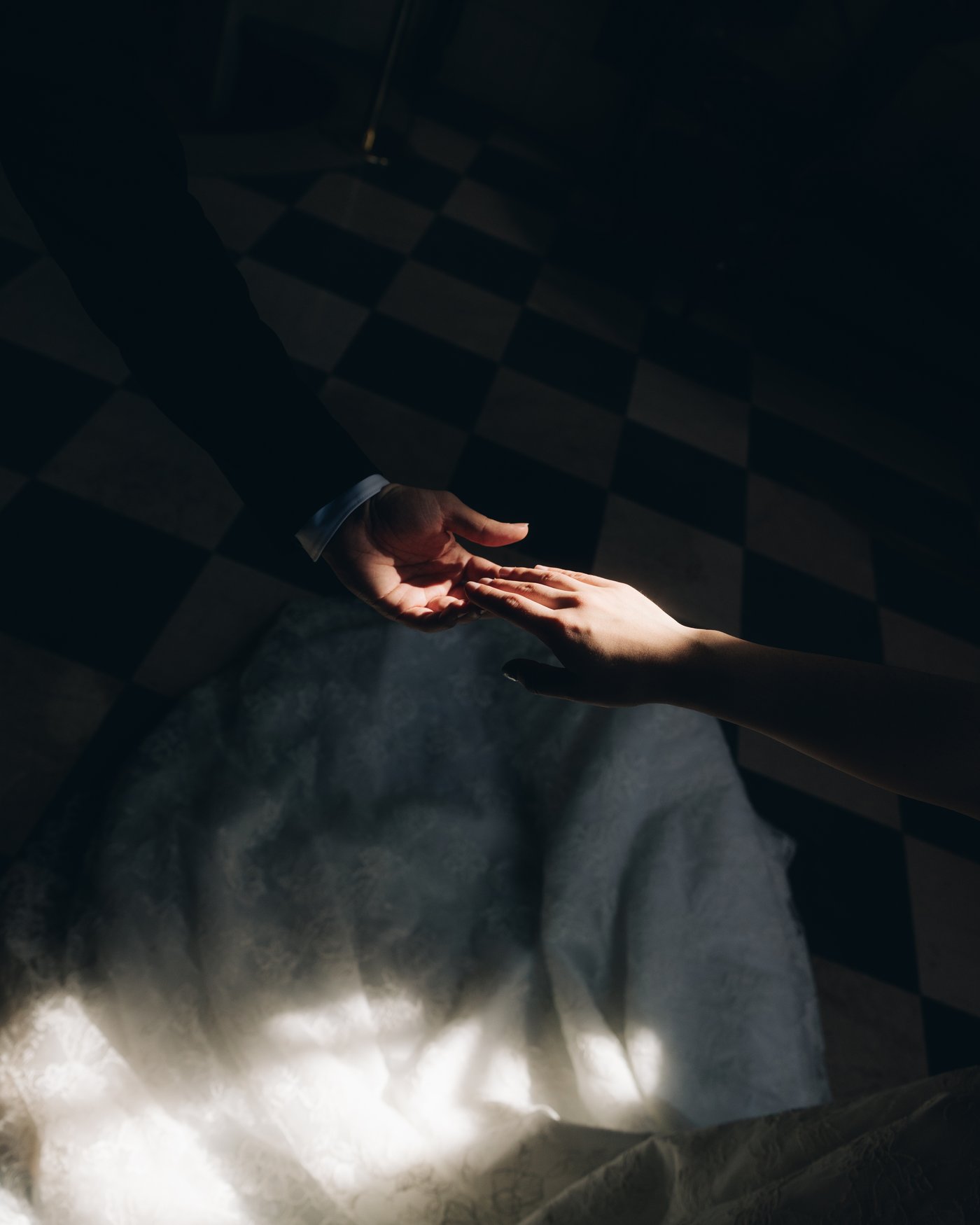A hand reaching across the dark toward the bride's dress