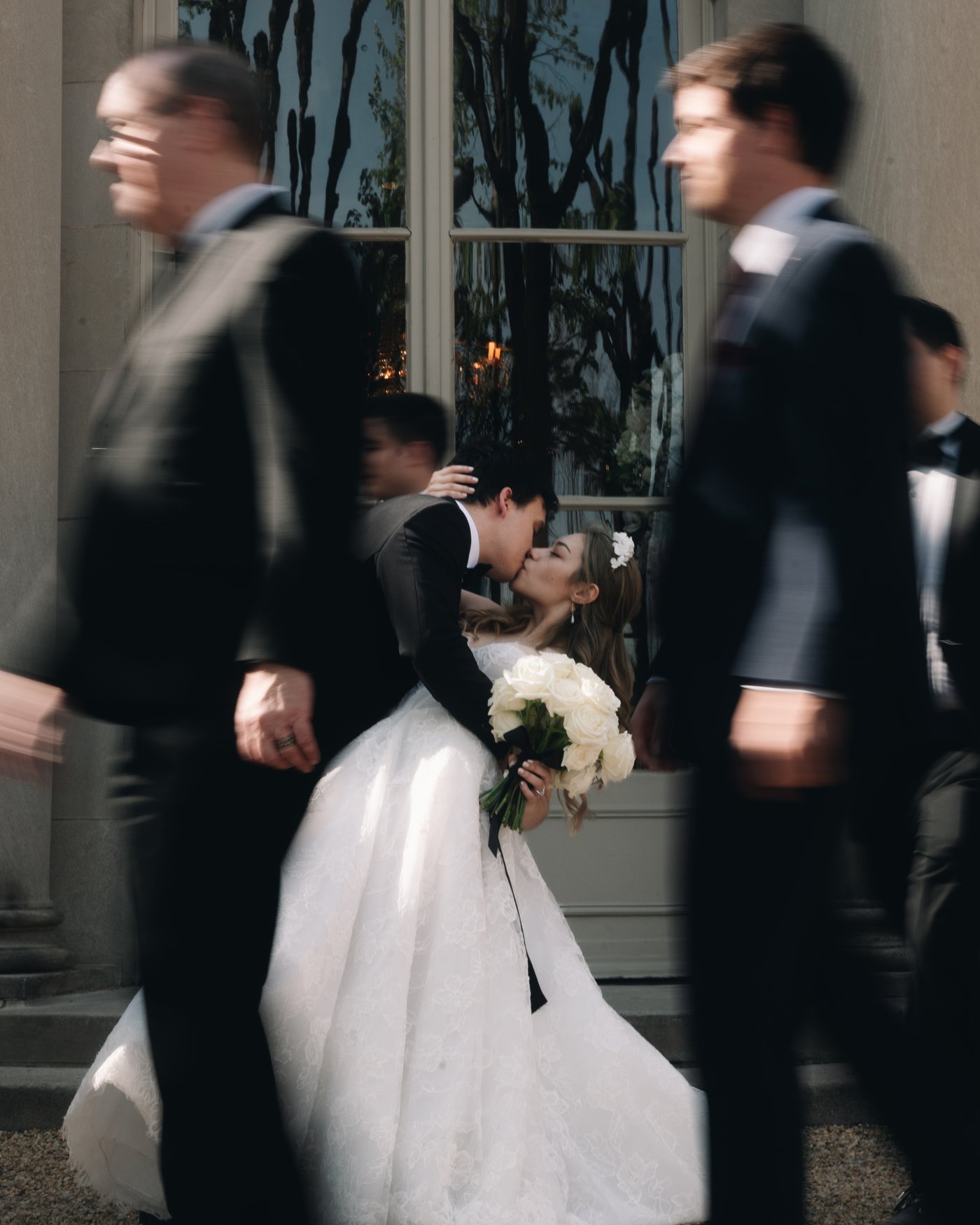 Guests moving past the bride, blurred, as she waits