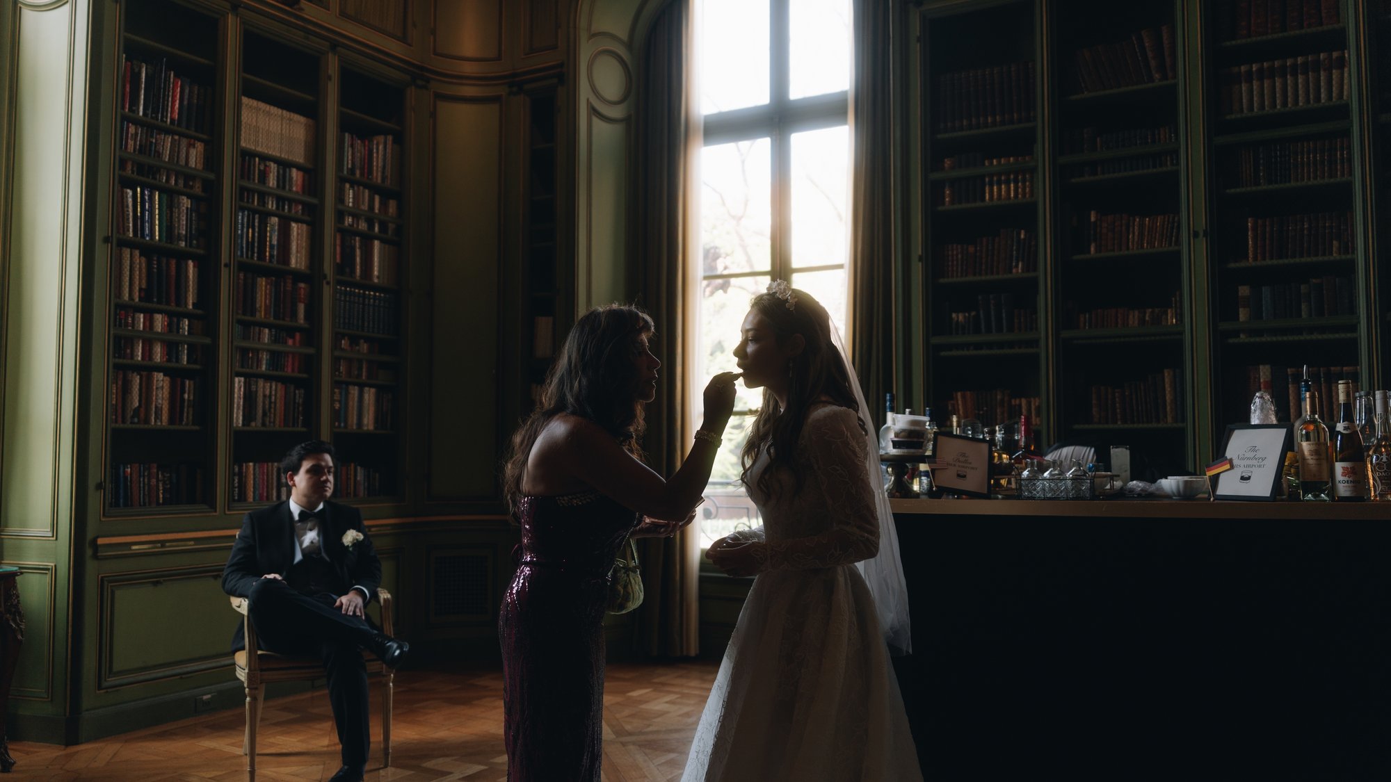 Two guests talking in the green library while a man sits reading the room
