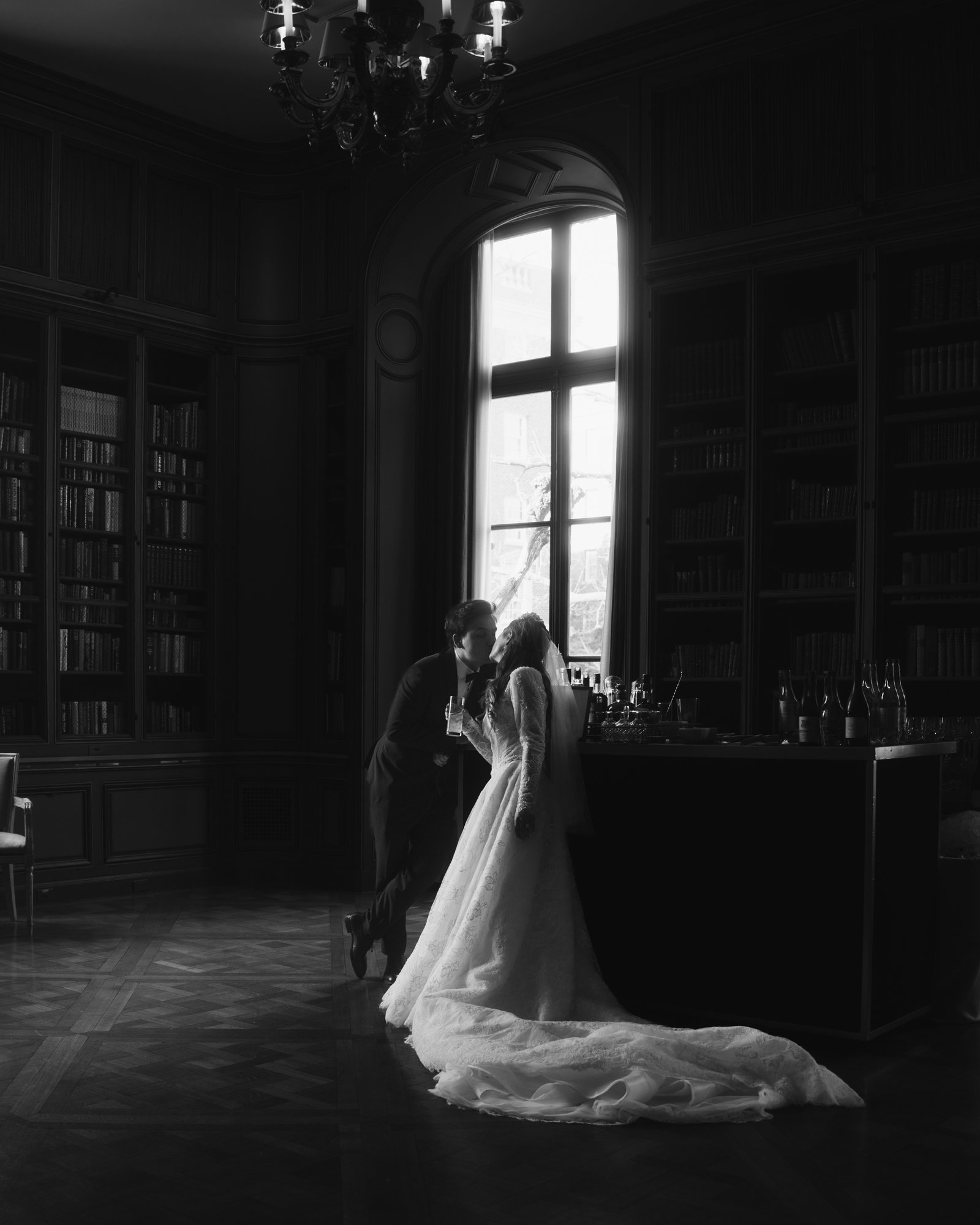 The bride alone in a dark panelled room, her train spread across the floor in the window light