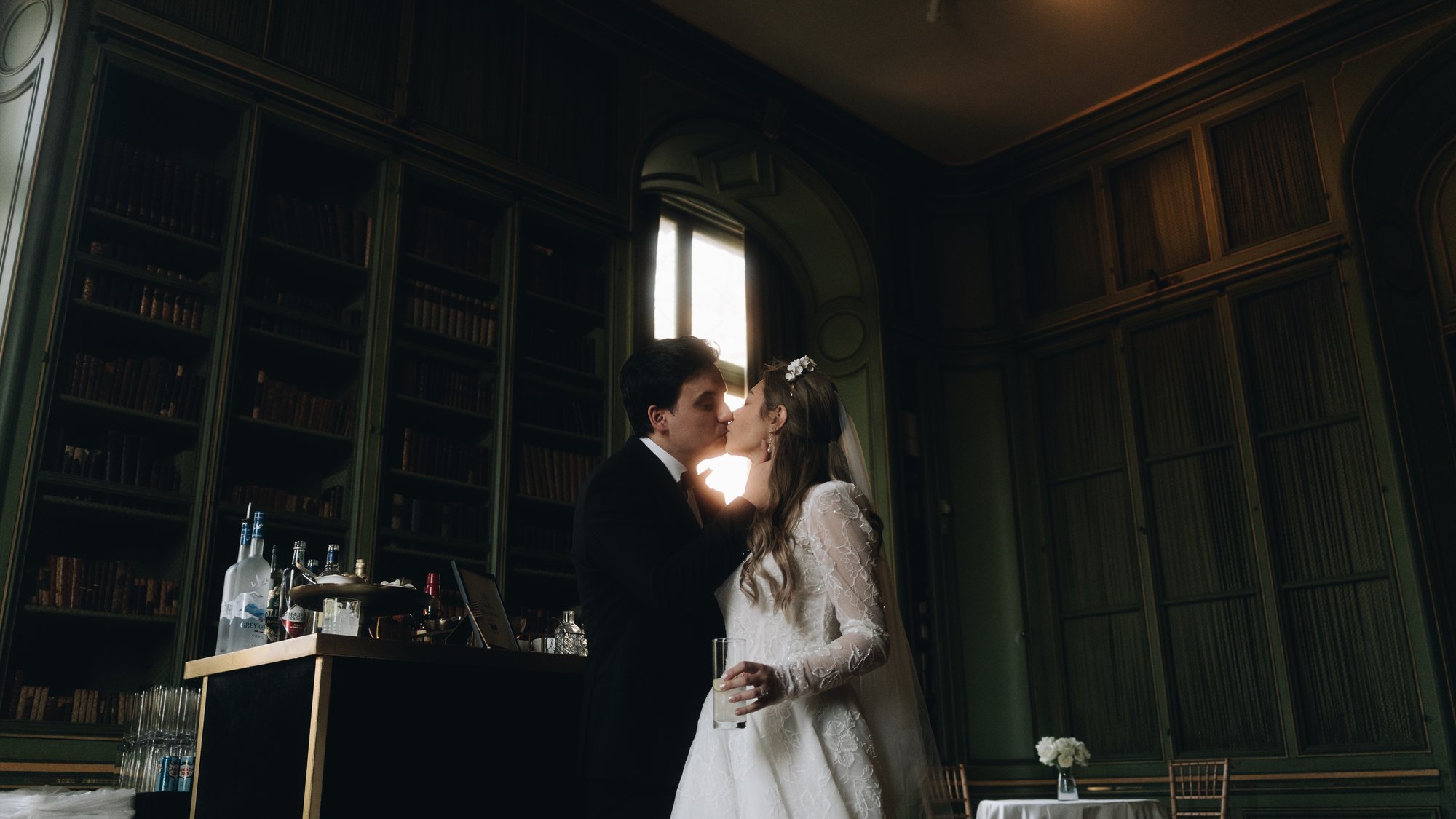The bride and groom together in the green library, lamplight and dark wood on every side
