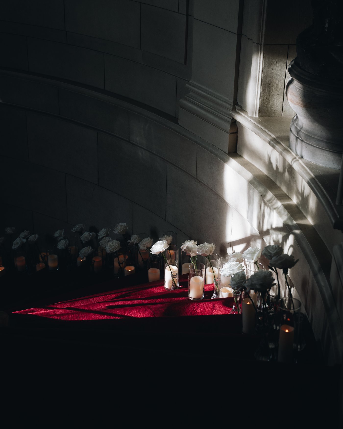 Candles running along the edge of the red carpet in the dark