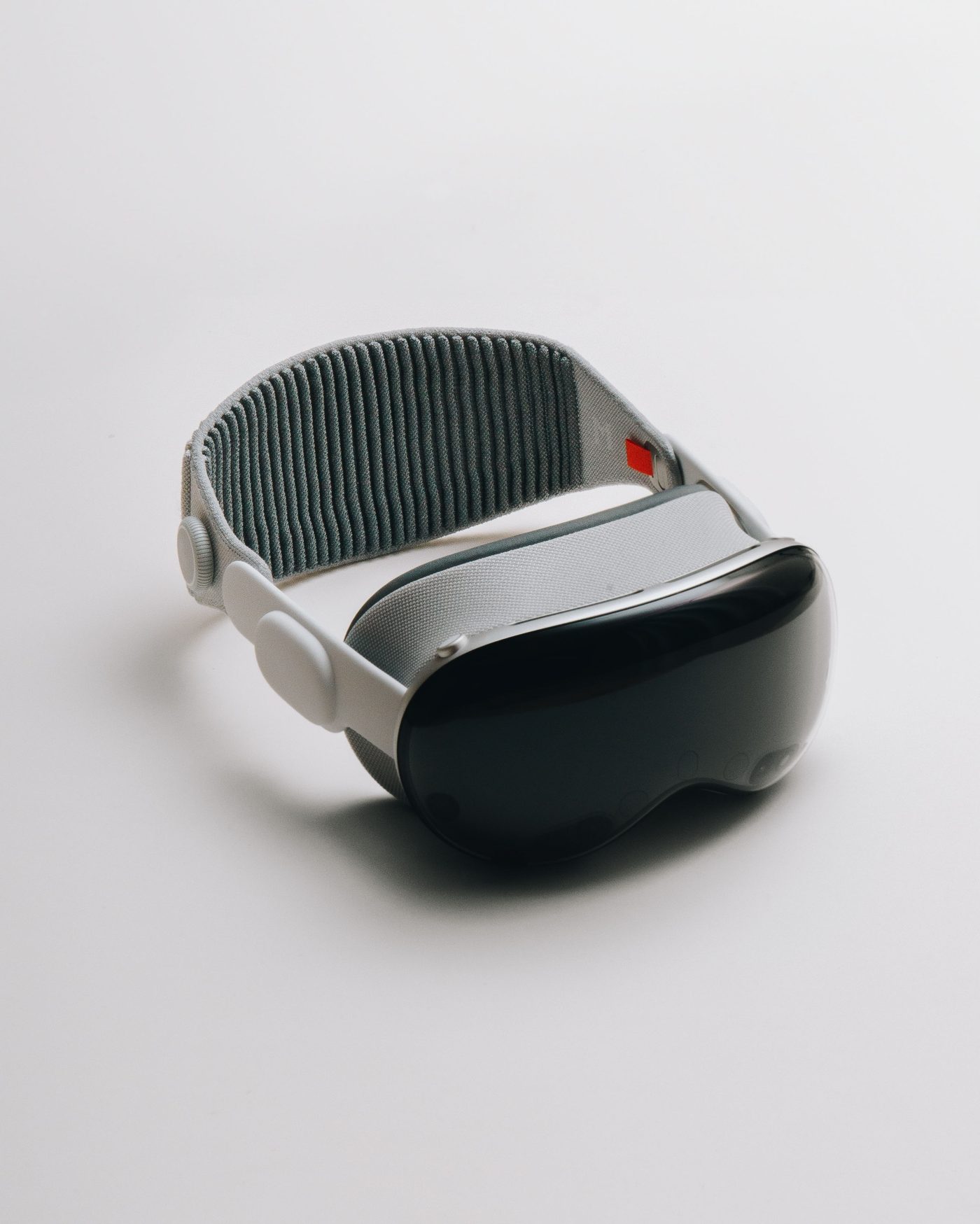 The headset three-quarters on against white, dark curved glass front and brushed silver frame
