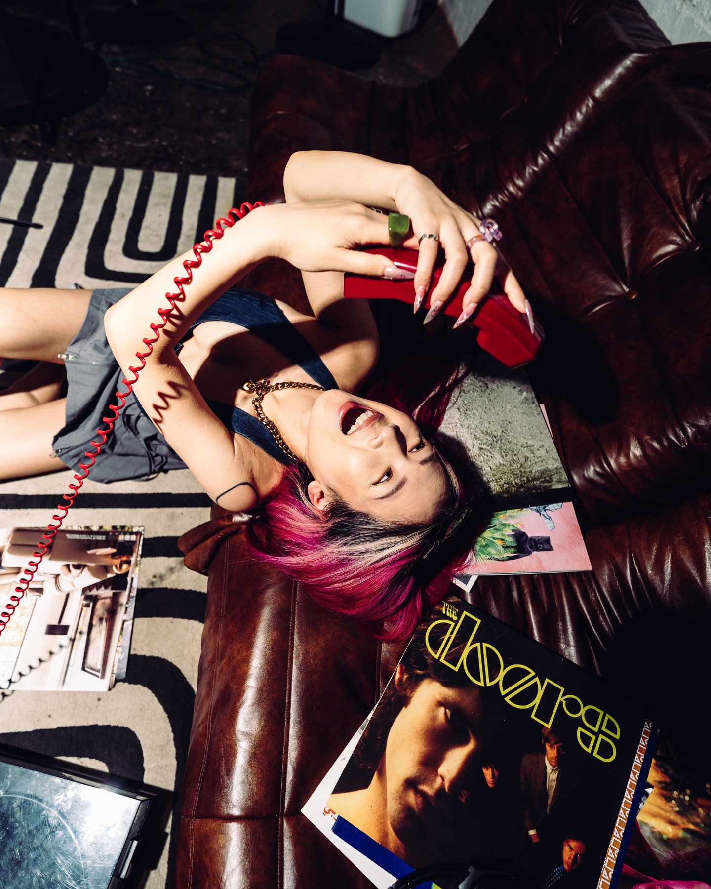 Lying on the leather sofa with the red phone, mouth open mid laugh