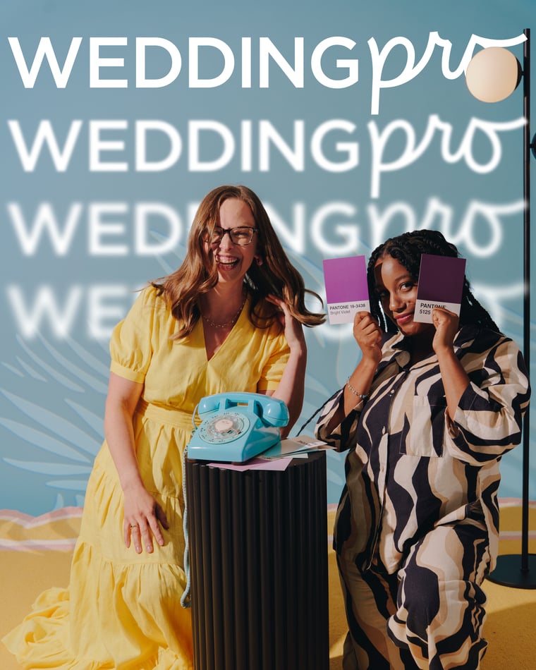 Two women either side of a fluted plinth with a teal rotary telephone on it, one leaning in a yellow dress, the other holding up purple swatch cards