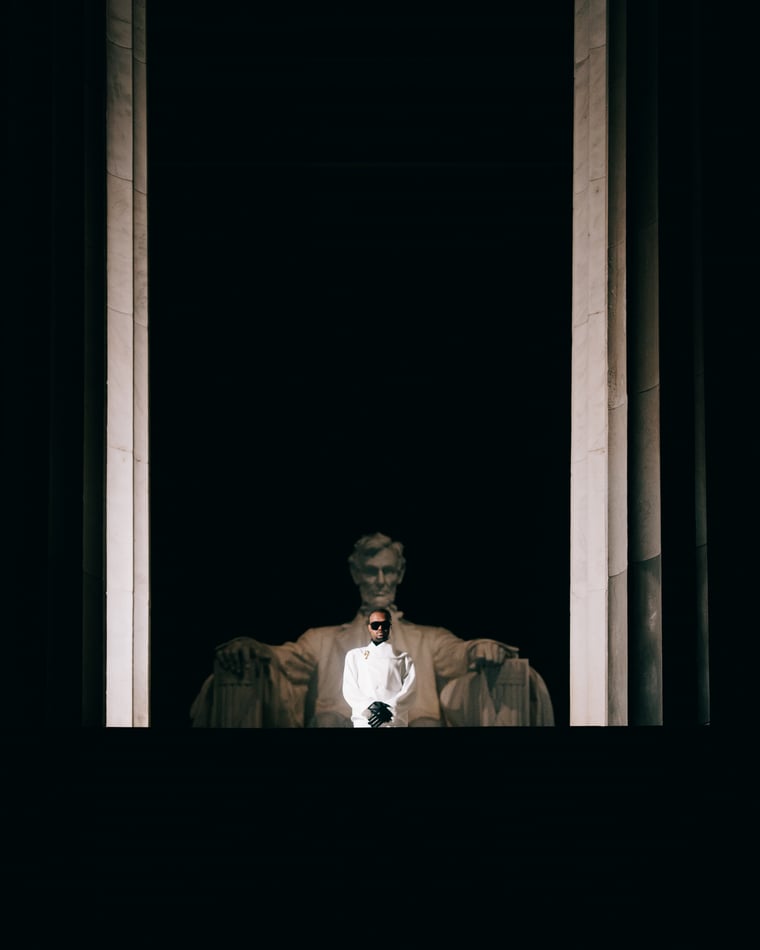 The seated Lincoln lit deep inside his colonnade, a single small figure standing below him in the dark