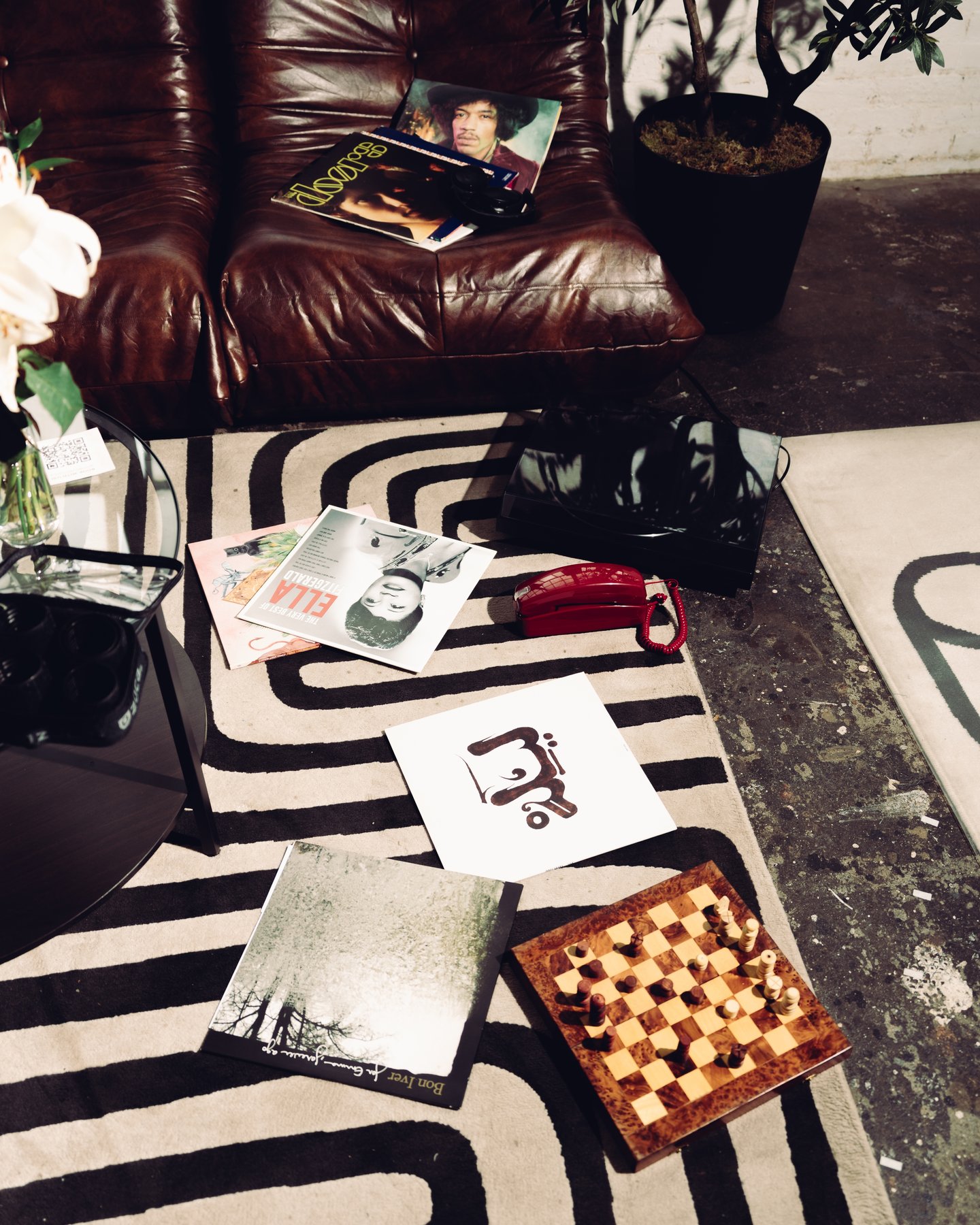 Overhead of the rug with a chessboard, a vase of flowers, a red bag and a magazine