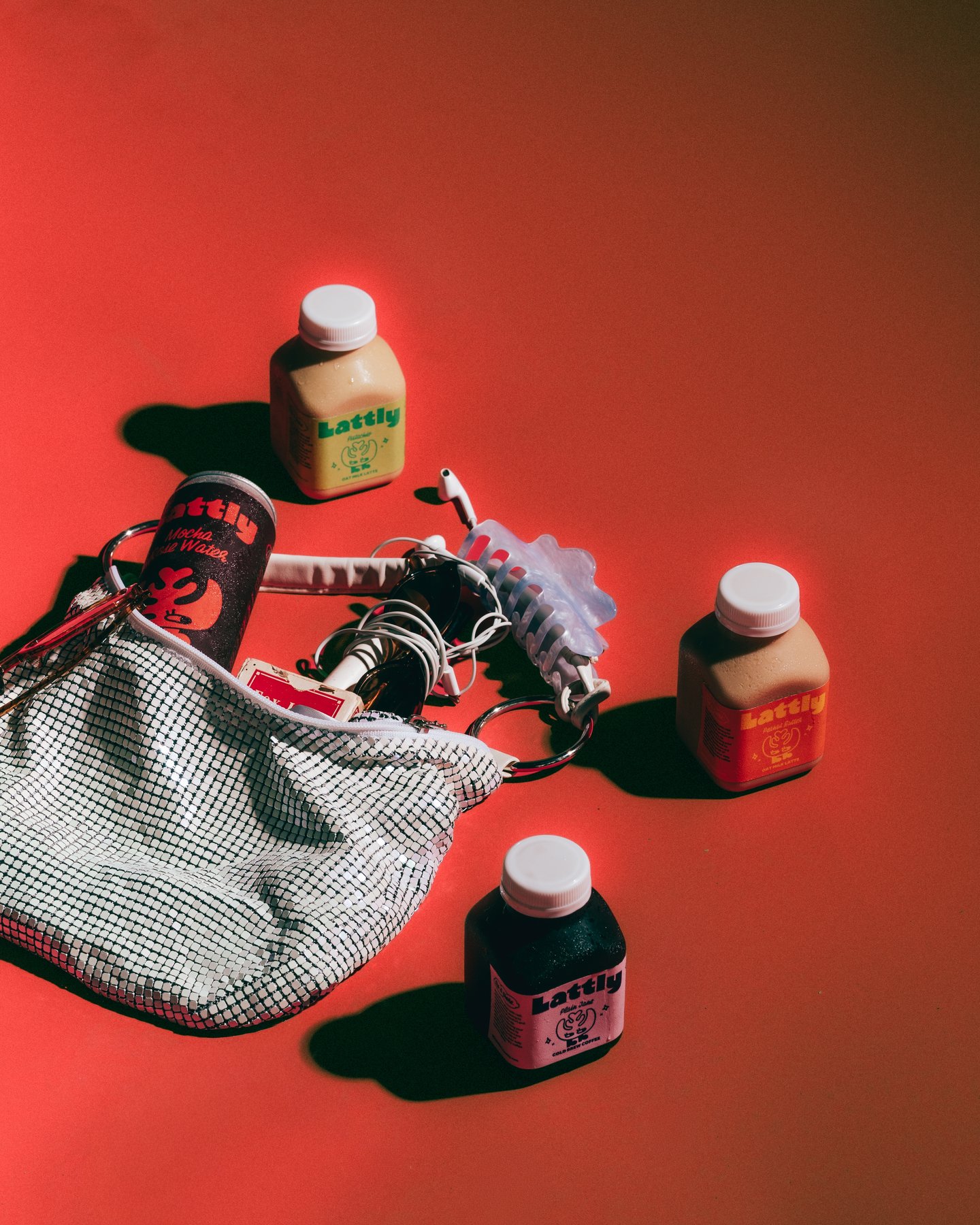 Lattly bottles scattered around a mesh bag and a beaded chain on red