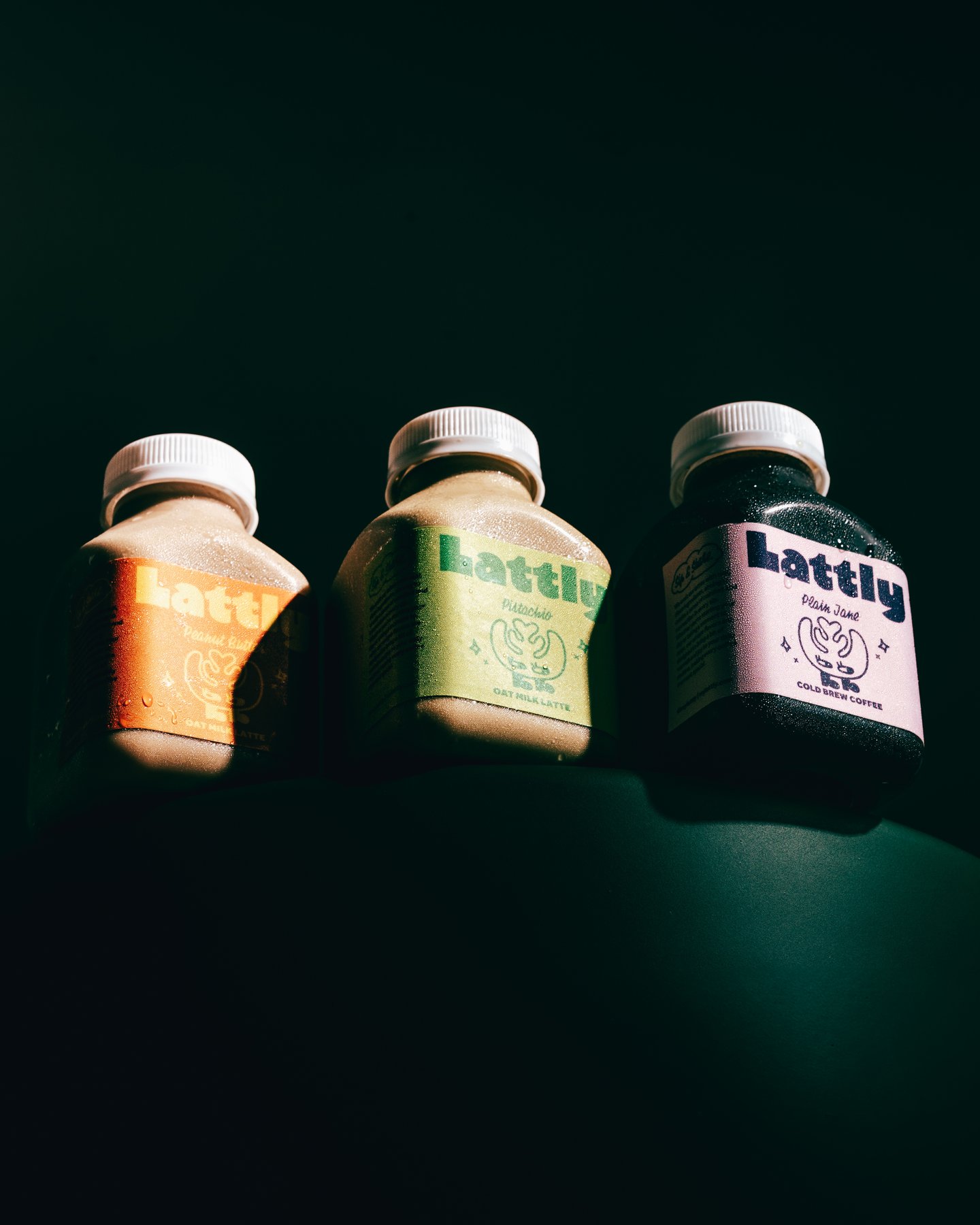 Three Lattly bottles lying in a row on dark green