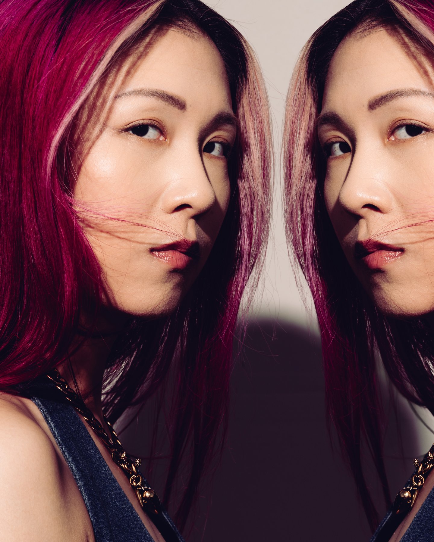 A mirrored double portrait, magenta hair on both sides