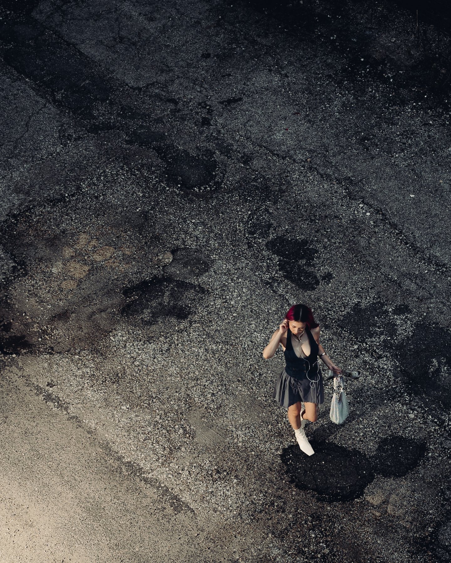 Overhead of a parking lot, one figure crossing the concrete