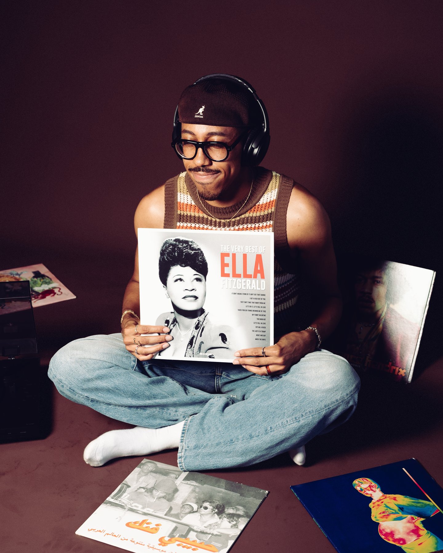 Kyle cross legged in headphones, the Ella record sleeve held up to the camera